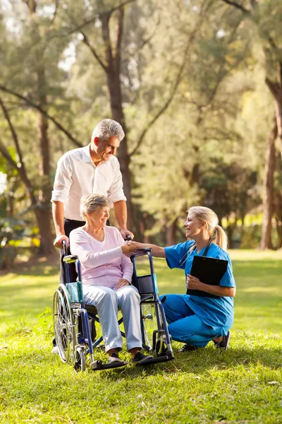 Female doctor greeting recovering senior patient in wheelchair