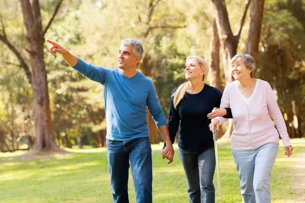 Middle aged couple taking elderly mother for a walk