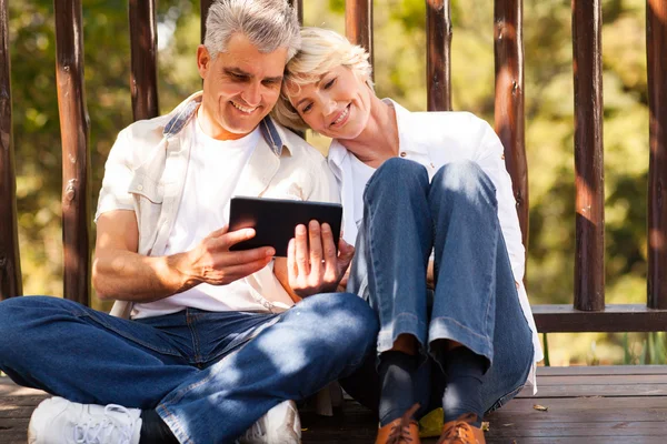 Senior couple using tablet computer outdoors