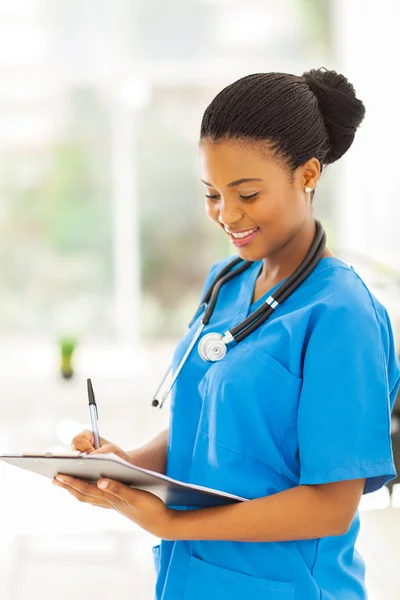 Young african medical intern doctor writing on clipboard