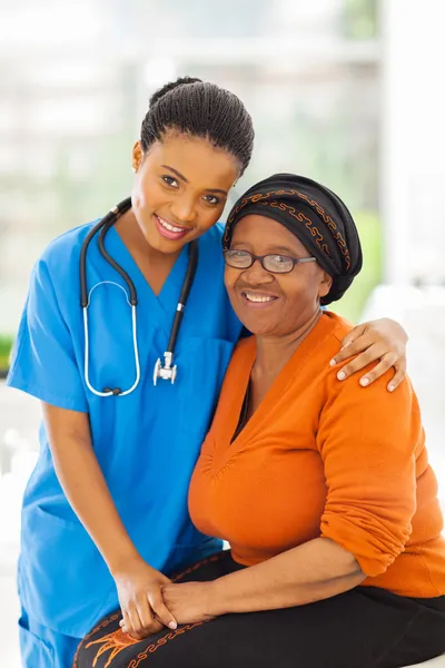 Caring african nurse and senior patient