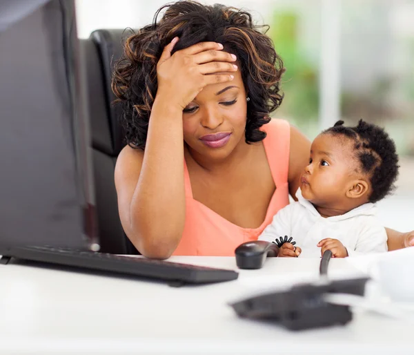 Frustrated african american businesswoman with baby in office