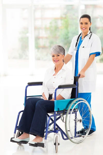 Young nurse pushing middle aged patient on wheelchair