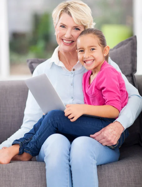 Little girl sitting on grandmother\'s lap with notebook computer