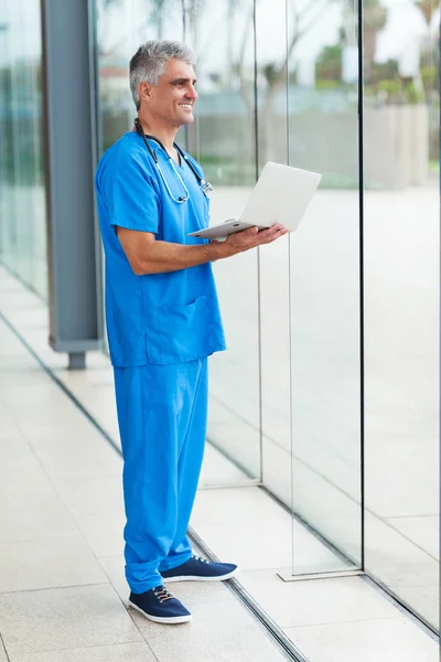 Middle aged healthcare worker holding laptop computer
