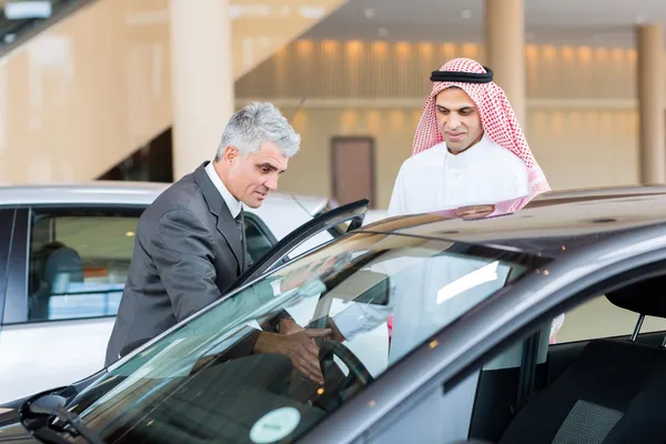 Car dealer showing car to Arabian buyer