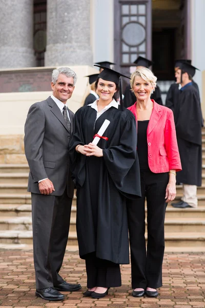 Graduate standing with parents at graduation