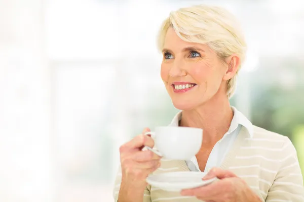 Thoughtful aged woman drinking coffee