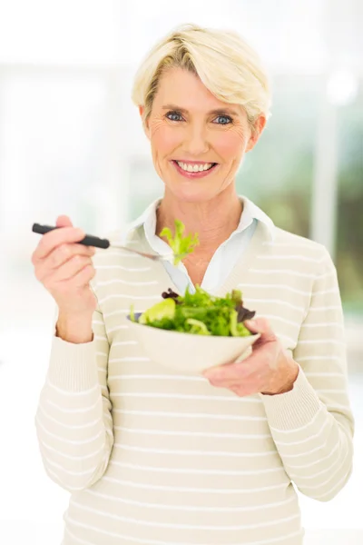 Middle aged woman eating salad