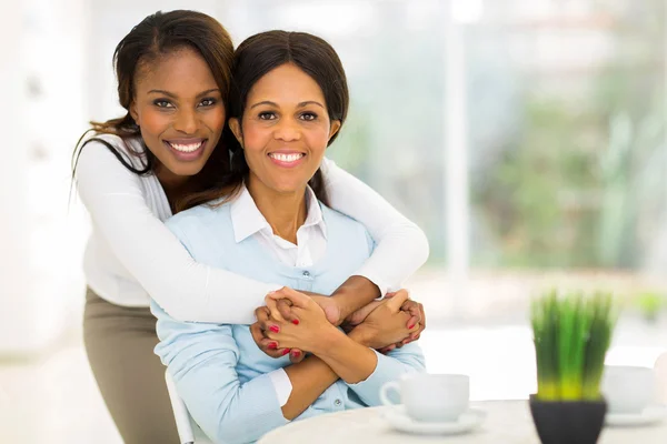 African daughter hugging middle aged mother