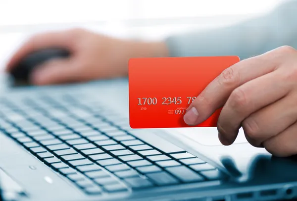 Man holding credit card in hand and entering security code using