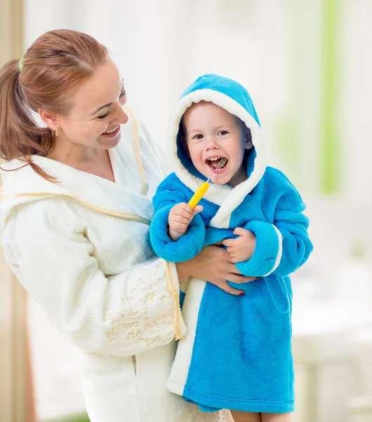 Mother and child brushing teeth together in bathroom. Dental hyg