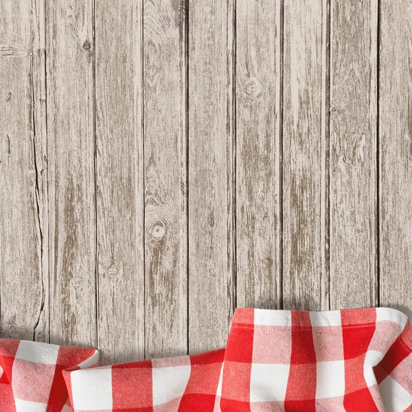 Old wooden table with red picnic tablecloth background