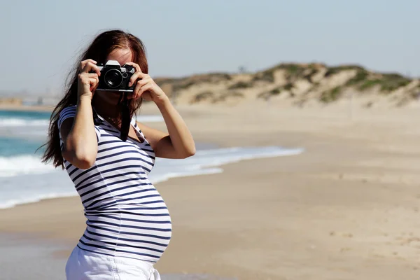Young pregnant woman holding vintage camera