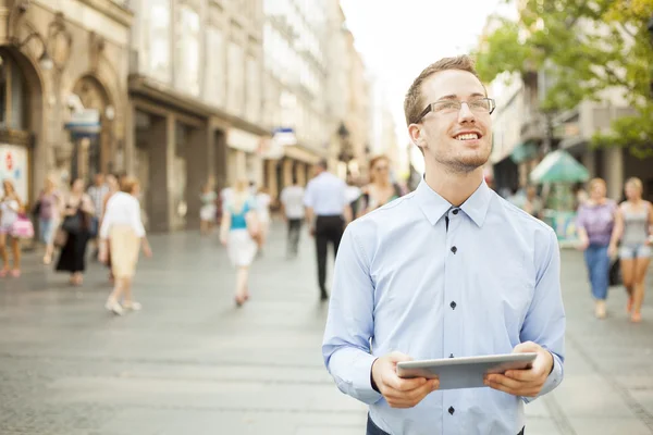 Man on street looking up, hold tablet computer in hands
