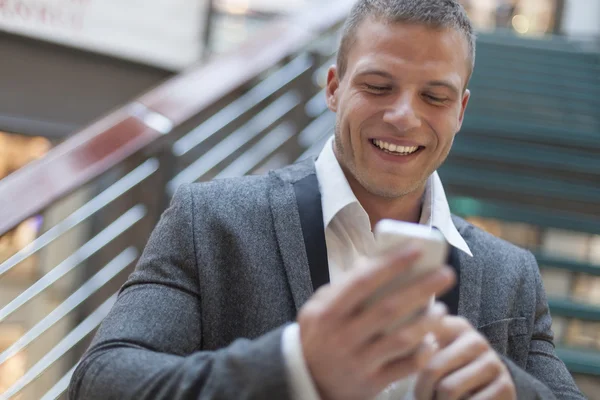 Happy businessman with smartphone in business building