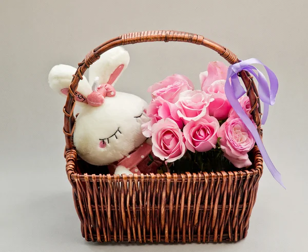 Pink roses in a basket and white rabbit toy