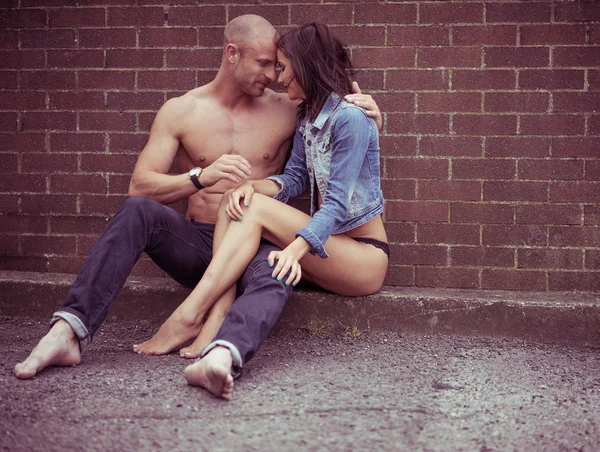 Sweet couple sitting in front of brick wall