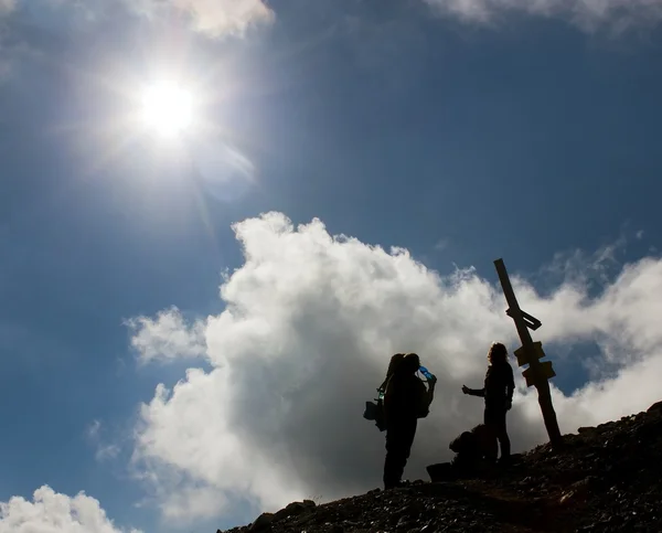 Silhouettes of tourists on mountains with sun and beautiful sky