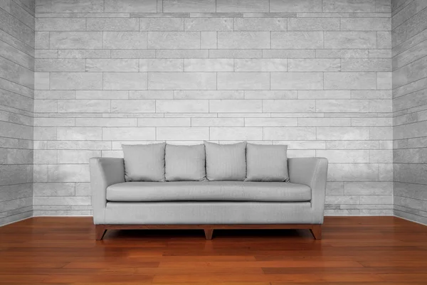 Gray couch chair on brown wooden floor and white wall