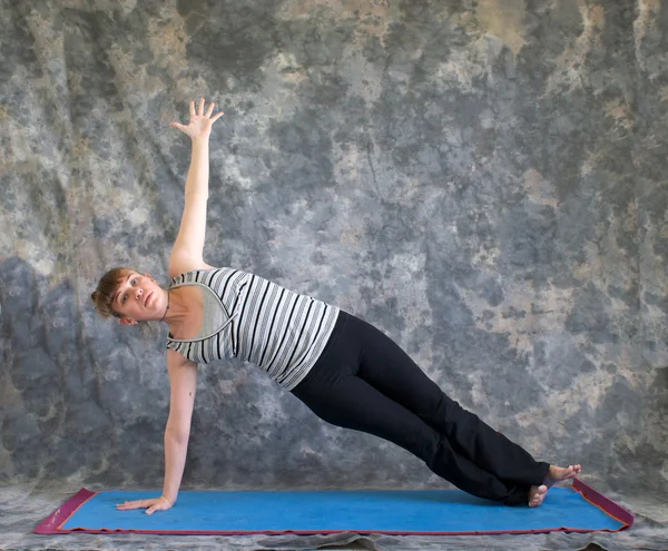 Woman doing Yoga posture Vasisthasana or side plank pose