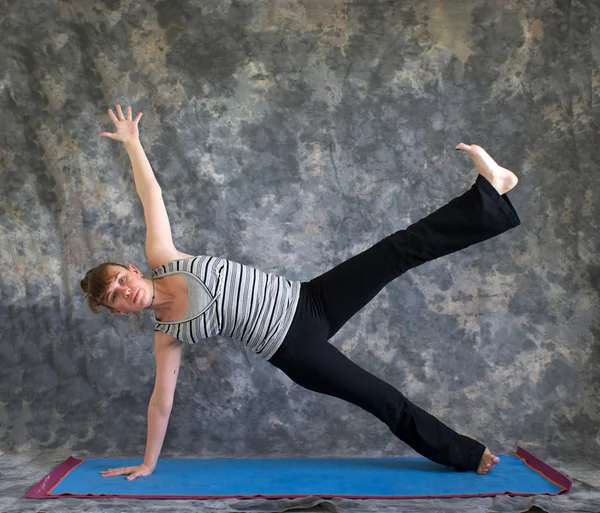 Woman doing Yoga posture Vasisthasana or side plank pose variati