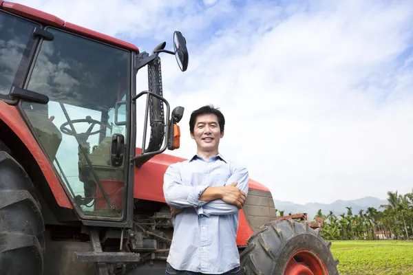 Happy middle aged asian farmer with old tractor