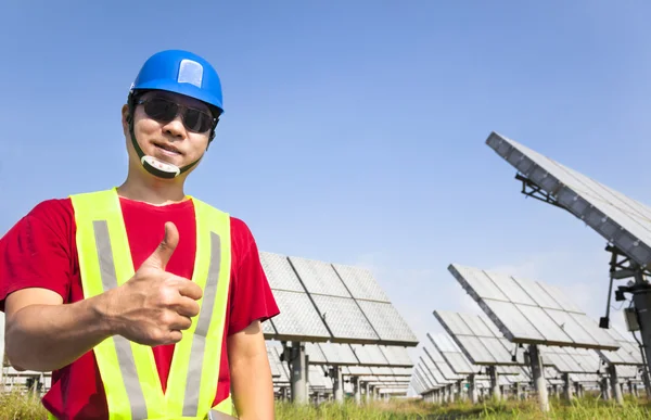 Happy worker with thumb up and standing before solar panel track