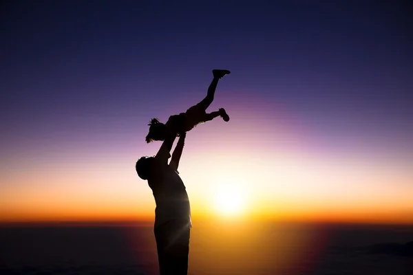 The silhouette of happy father and little girl with sunrise back