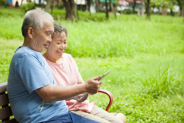 Happy asian seniors couple with tablet pc