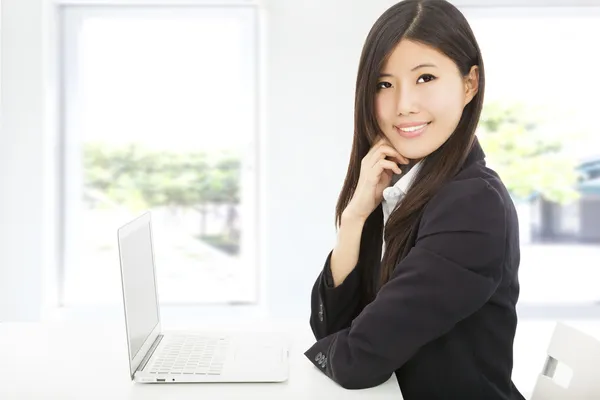 Beautiful young businesswoman with laptop in office