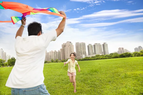 Happy family playing colorful kite in the city park