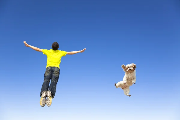 Relaxing young man and dog jumping in the sky