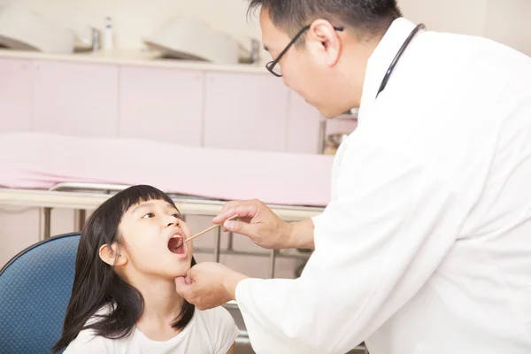 Pediatrician examining kid throat with tongue depressor