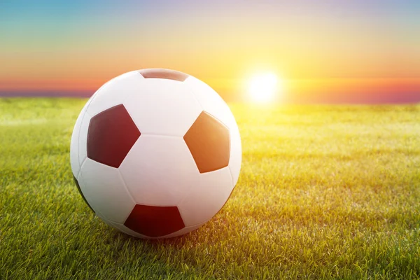 Soccer ball on the field with sunset