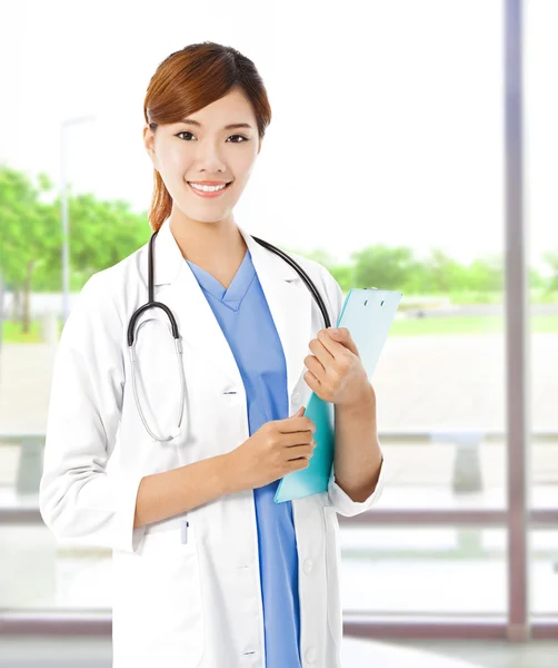 Pretty young female doctor standing and holding document