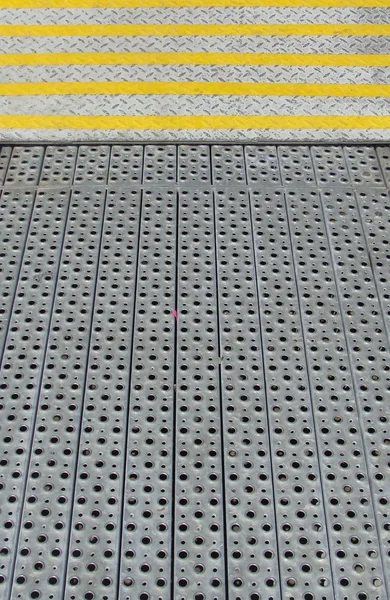 Detail from steel security steps surface with yellow stripes