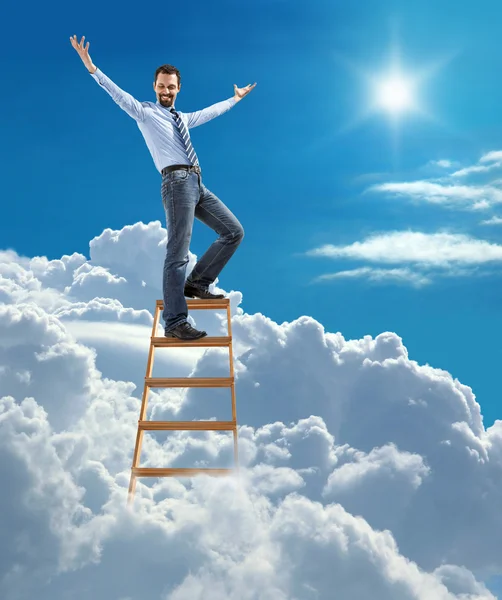 Young confident businessman standing at the ladder high in the sky spread his arms