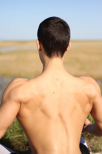 Muscle young man showing his back muscles