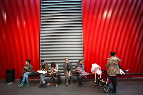 People sitting down on a red bench