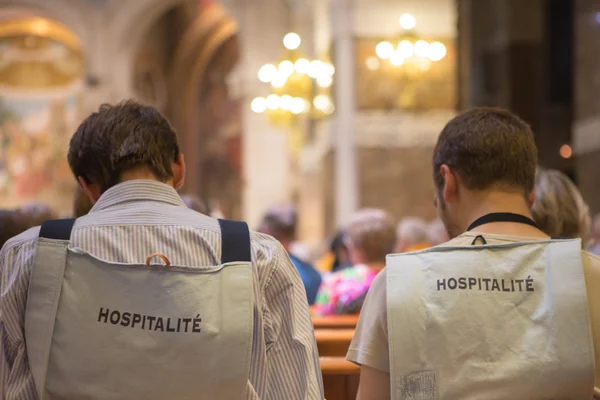 Back of volunteers in Lourdes in the church of Lourdes