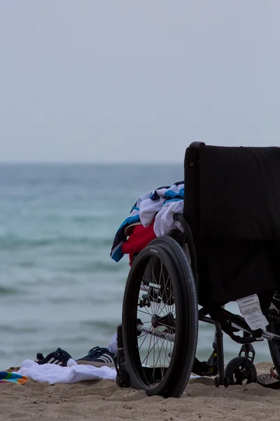 Empty wheel chair on the beach with clothes