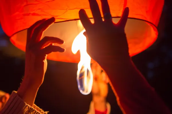 Close up of hands manipulating a big flying lantern at night