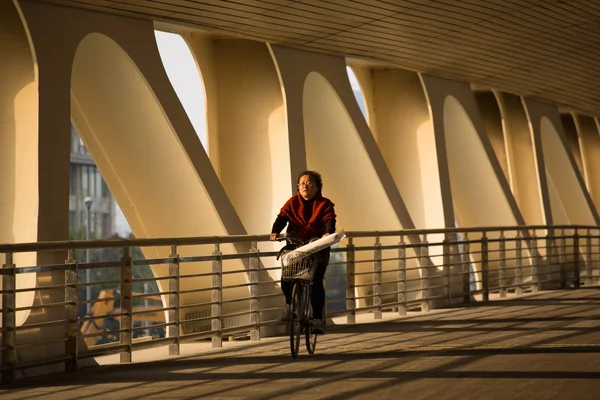 Woman cycling under a bridge with French taste