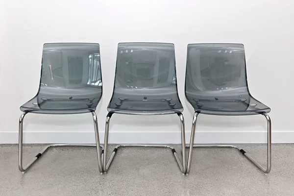 Three plastic chairs against wall