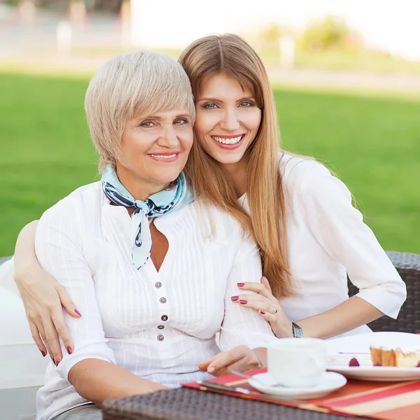 Adult mother and daughter drinking tea or coffee