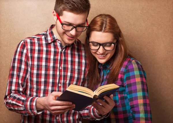 Young couple in clothes and stylish hipster glasses reading a bo