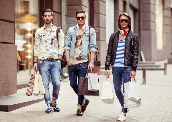 Three Young male fashion metraseksuals shop. Men shopping walk.