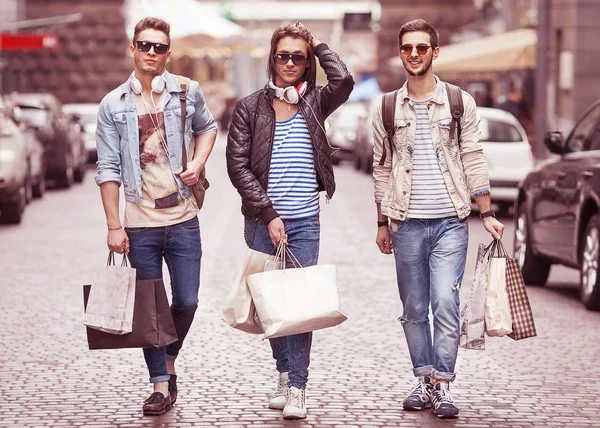 Three Young male fashion metraseksuals shop. Men shopping walk.