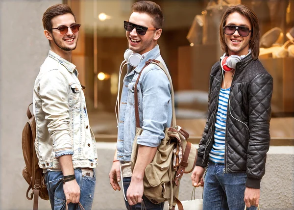 Three Young male fashion metraseksuals shop. Men shopping walk.